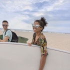 Young couple carrying surfboards on Rockaway Beach, New York State, USA